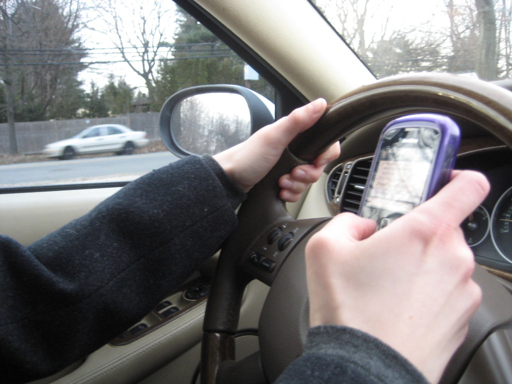 A distracted driver holds a cell phone while driving.