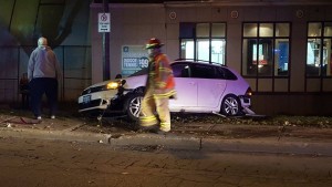 crashed car with firefighter walking in front of it