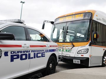 bus with "Don't Drink and Drive" sign parked behind a police cruiser
