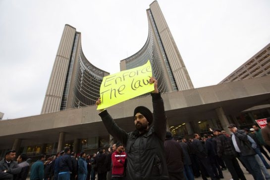 Todd Korol/Toronto Star A taxi cab driver holds a protest sign outside city hall.