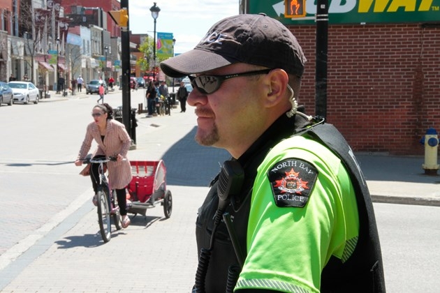 Bike Patrol officer Constable John Cook is about to warn a cyclist illegally riding on a downtown sidewalk. Photo by Chris Dawson.