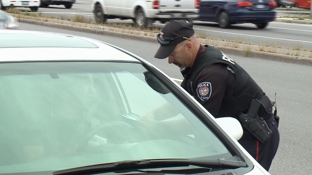 A police officer talks to a driver at the side of the road.