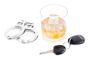 An alcoholic drink sits next to car keys and handcuffs.