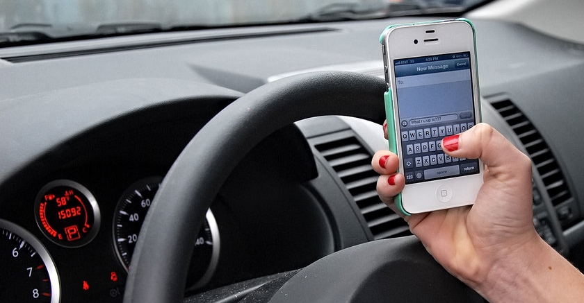 Texting and driving stock photo with an iPhone.
